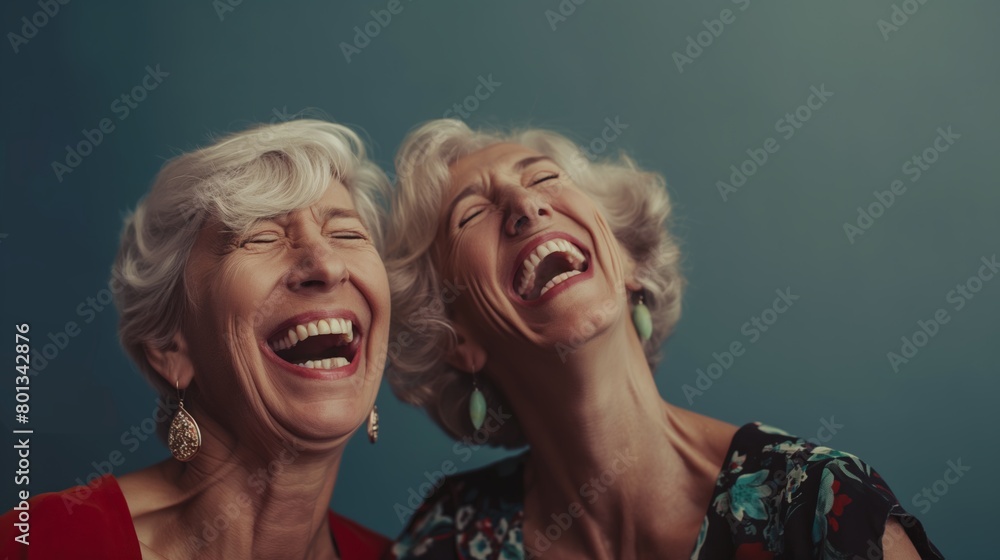 Two mature women friends laughing together with giant smiles Two mature women friends laughing together with giant smiles