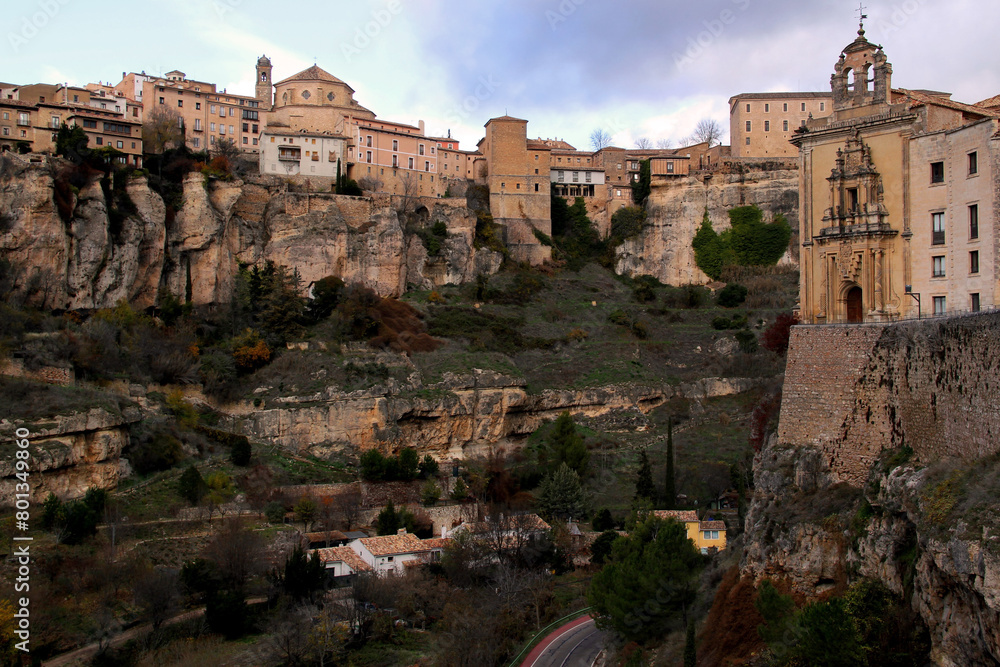 Obraz premium View of the gorge, overhanging cliffs and the building of the Antiguo Convento de San Pablo against a dramatic sky in the city of Cuenca, near Madrid, Spain