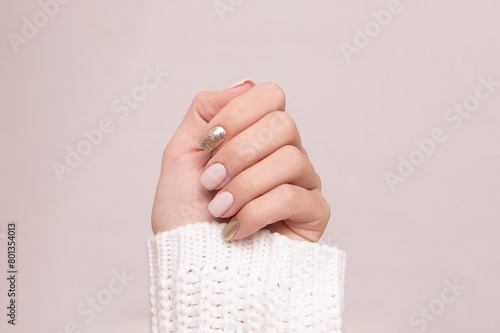 
Beautiful female hand with beige and golden manicure nails on white background
