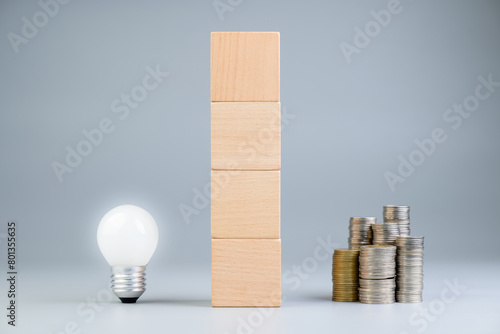 Light bulb and heap of coins, with stack of wood cubes as the wall between it, the money that is on the other side of the crative idea, making money concept