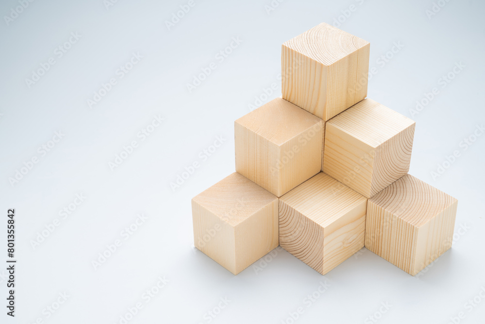 Stack of wood cubes built as step stairs pyramid on white background, wooden toy, permanent, and strong success Stack of wood cubes built as step stairs pyramid on white background, wooden toy, permanent, and strong success