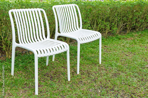 Two plastic white chairs in the garden backyard, garden ladder back chairs outside the house © patpitchaya