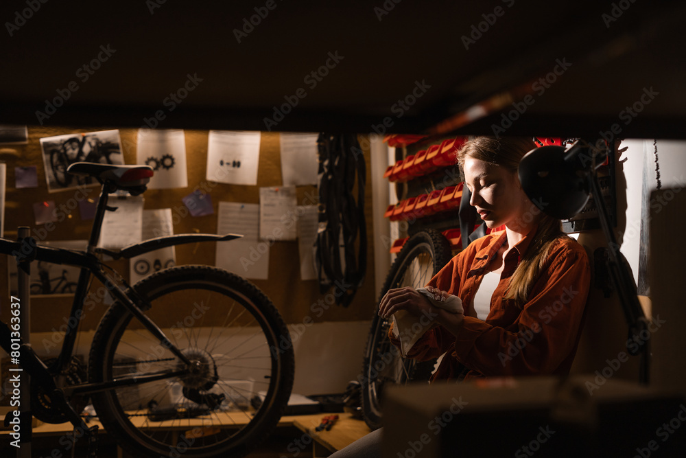 Portrait of woman wipes her hands with a rag while working at a repair shop, bicycle maintenance.