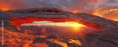 A rock archway formation against a vibrant sunset, casting a long shadow across a desert landscape 