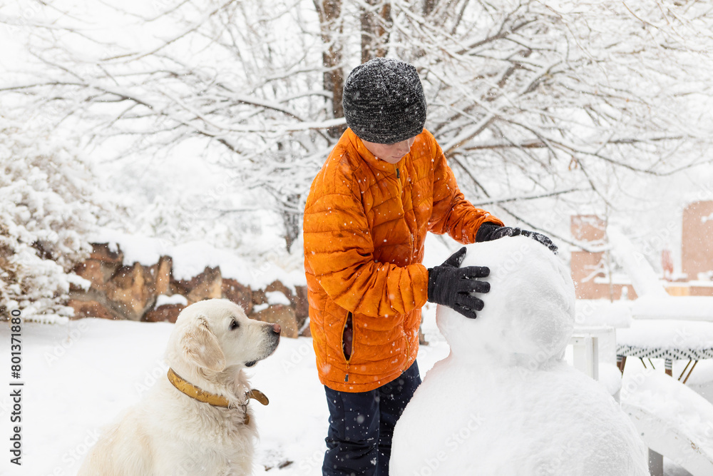 Boy with his dog building snowman Boy with his dog building snowman