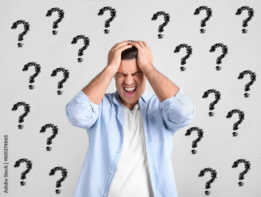 Amnesia. Stressed man and question marks on light background Amnesia. Stressed man and question marks on light background
