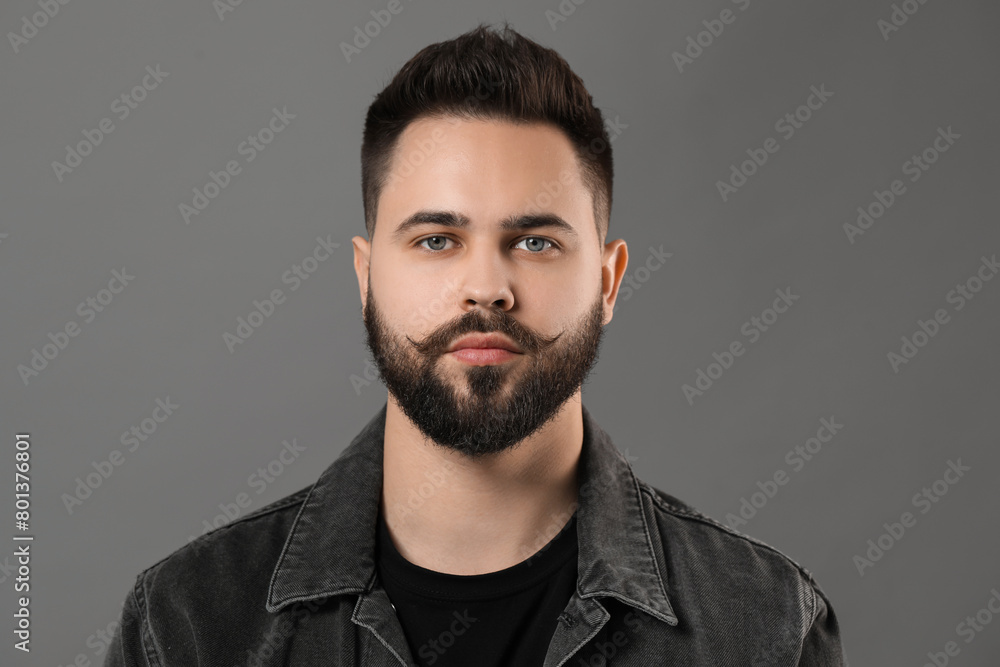 Obraz premium Portrait of young man with mustache on grey background