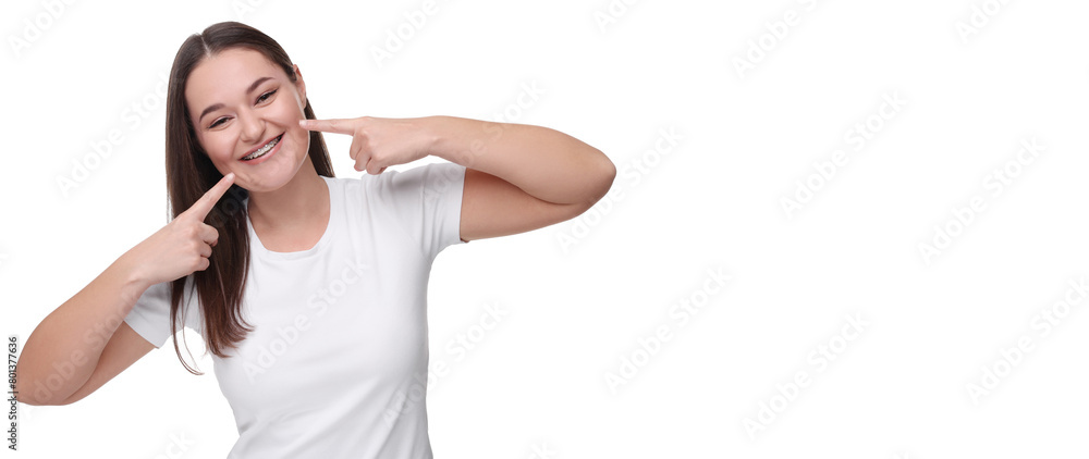 Smiling woman pointing at her braces on white background. Banner design with space for text Smiling woman pointing at her braces on white background. Banner design with space for text