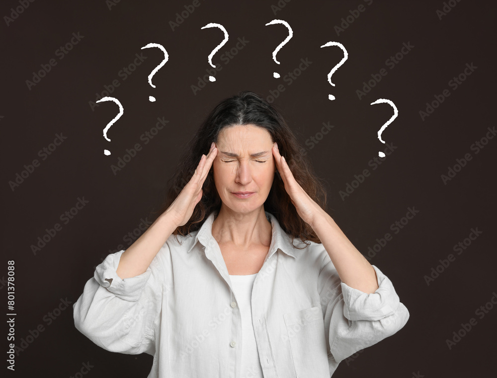 Amnesia. Confused woman and question marks on brown background