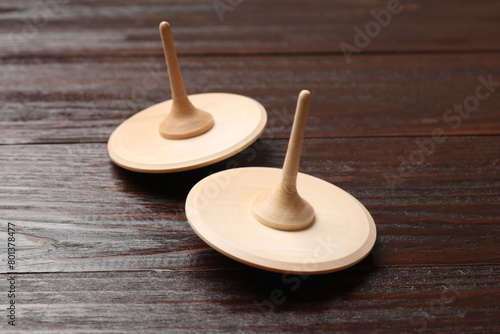 Two spinning tops on wooden table, closeup