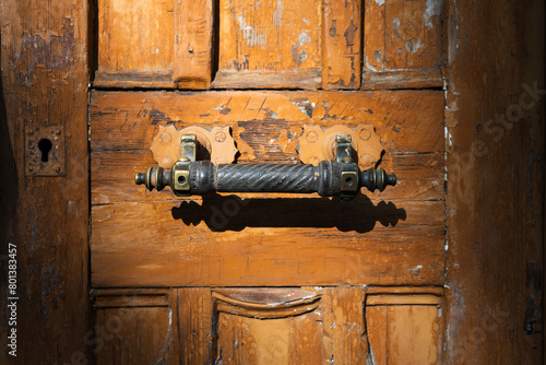 Vintage door handle on an yellow wooden door . Close up