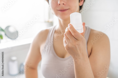 Photos Close up woman holding natural crystal alum deodorant in modern bathroom