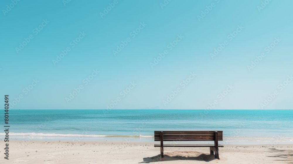 Serene beach scene with empty bench overlooking clear blue ocean