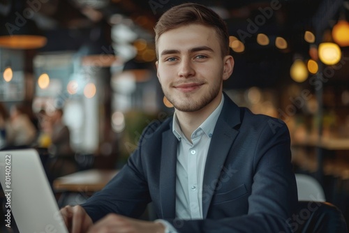 Close-up portrait of a smiling young businessman, developer man in a suit sitting in a modern office at a desk and working on a laptop, Generative AI