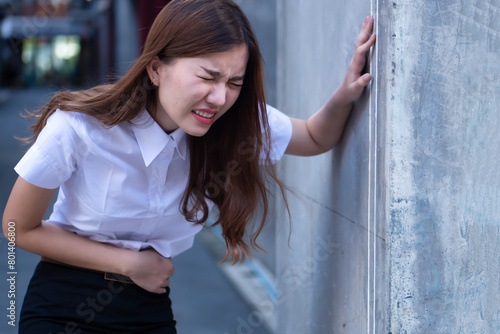 Sick asian woman suffering from stomach ache, concept of menstrual period cramp, abdominal pain, food poisoning, gastritis, acid reflux or colon cancer photo