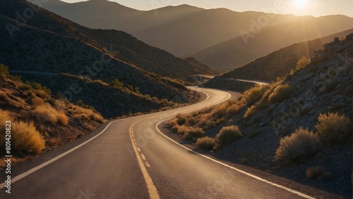 Empty road winding through mountains at sunset
