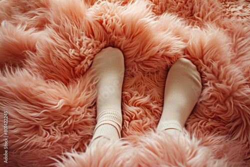 Feet in peach socks on a fluffy carpet. © July P