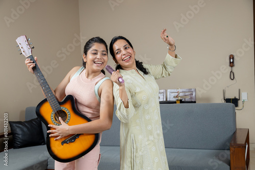 Indian Mother singing and Teen daughter playing guitar together , Mother and Daughter singing and dancing at home candid moments