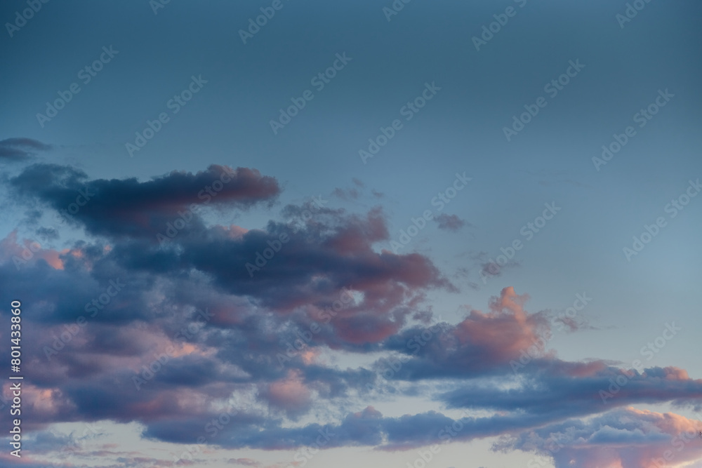 Dark clouds in the blue sky illuminated by the setting sun, clouds in the evening sunset