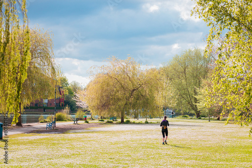 Female jogging on meadow next to river thames, evening spring