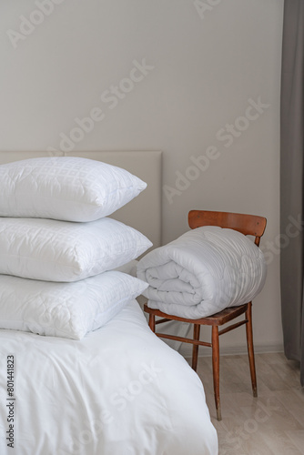 A bed with white pillows and a blanket, next to a bedside table with a lamp, daylight