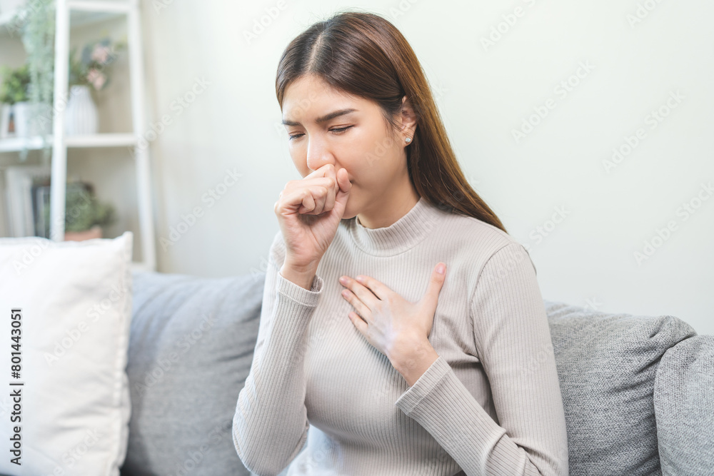Unhealthy sickness asian young woman, girl unwell with coughing, have cold, sore throat on sofa, couch at home, suffering with symptom cough feeling bad. Health care of Coronavirus, covid-19 concept. Unhealthy sickness asian young woman, girl unwell with coughing, have cold, sore throat on sofa, couch at home, suffering with symptom cough feeling bad. Health care of Coronavirus, covid-19 concept.