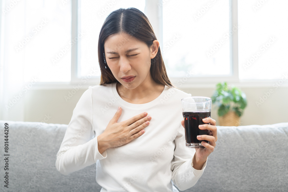 Acid reflux disease, suffer asian young woman, girl hand holding a glass of cola, have symptom gastroesophageal, heartburn pain on chest when drinking sparkling, soft water. Healthcare medical concept Acid reflux disease, suffer asian young woman, girl hand holding a glass of cola, have symptom gastroesophageal, heartburn pain on chest when drinking sparkling, soft water. Healthcare medical concept