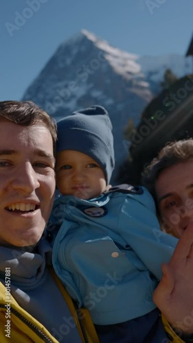 POV of cheerful parents and little son waving hello and smiling in camera. Happy family enjoys autumn trip in highland of Switzerland closeup Vertical footage.