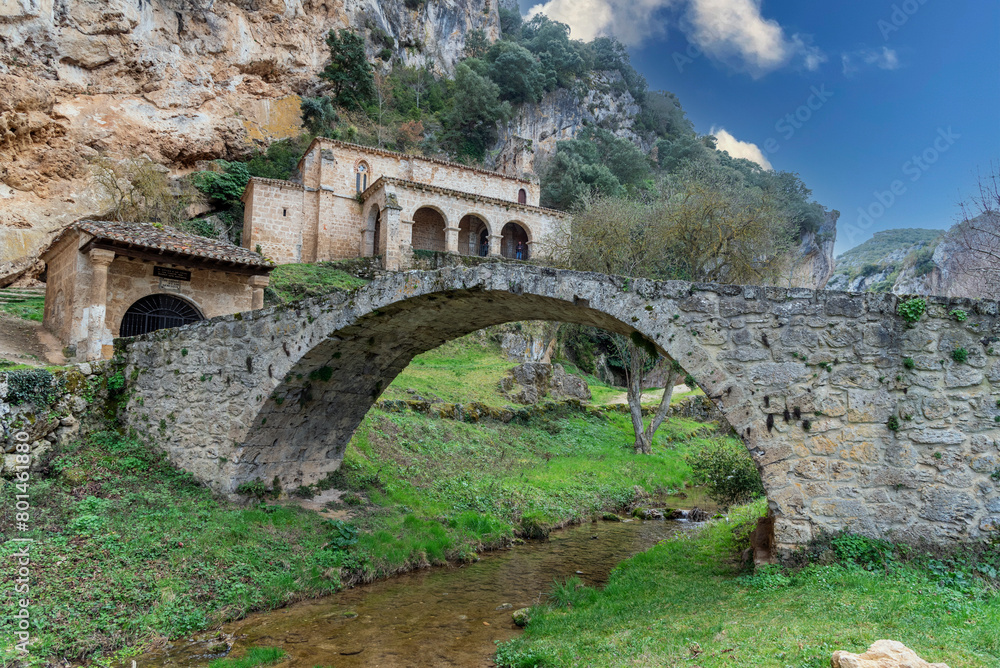 Fototapeta premium Hermitage of Santa María de la Hoz in the small village of La Tobera, built on a hill in front of a Roman stone bridge belonging to the municipality of Frías.