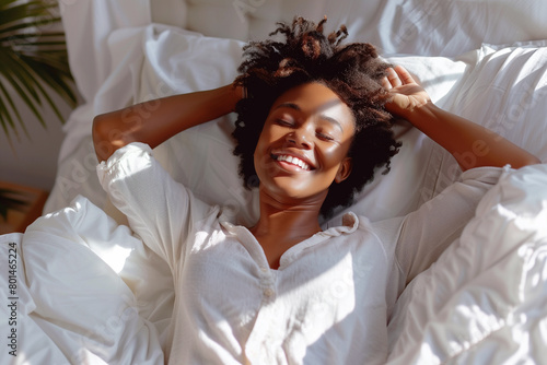 Cheerful African Woman Lying in Bed and Stretching Her Arms – Morning Routine and Wellness Concept. joyful African woman enjoying her morning routine, lying in bed and stretching her arms.