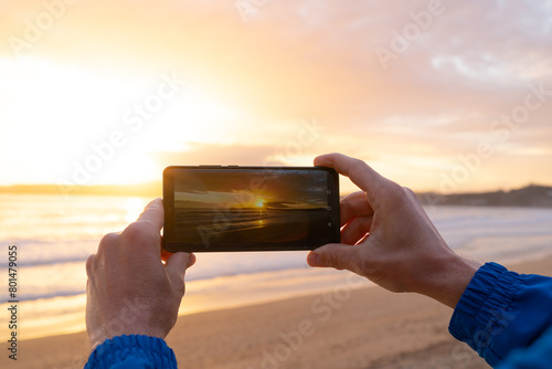 Hands taking photos with a phone at sunset. Galicia Spain.