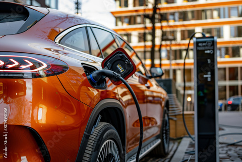 electric car was charging at an outdoor station in front of a modern building.  © Denis