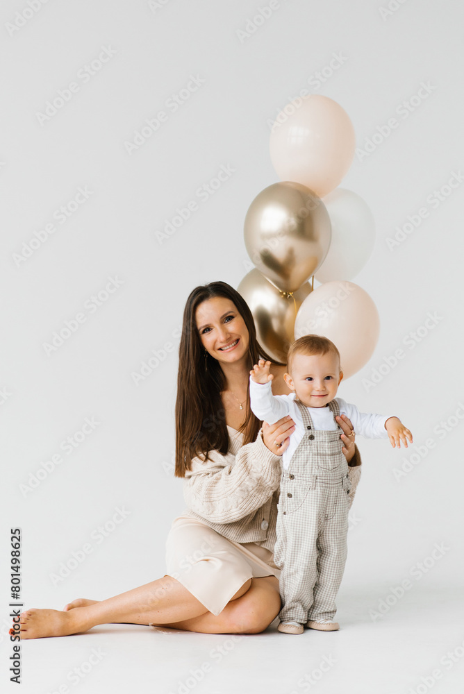 Happy woman and child pose for a photo with golden and white balloons. The scene is happy and joyful Happy woman and child pose for a photo with golden and white balloons. The scene is happy and joyful