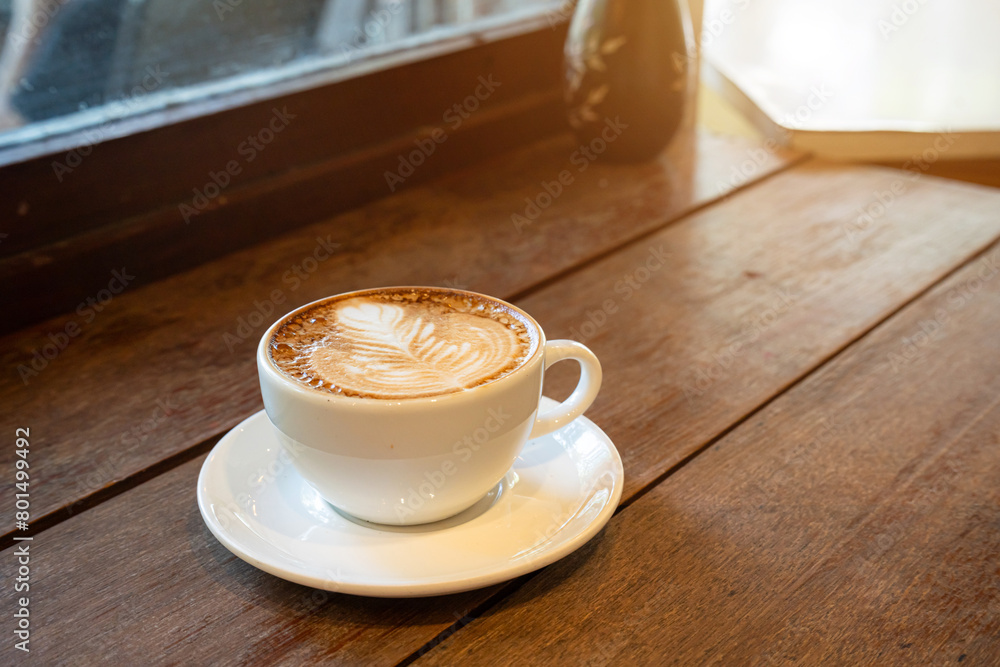 Obraz premium Hot coffee latte with latte art milk foam in cup mug on wood desk on top view. As breakfast In a coffee shop at the cafe,during business work concept,vintage style