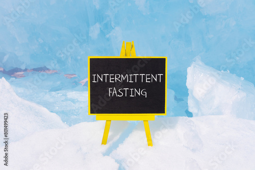 Intermittent fasting symbol. Concept words Intermittent fasting on beautiful yellow black blackboard. Beautiful blue ice background. Healthy lifestyle intermittent fasting concept. Copy space.