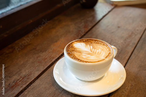 Hot coffee latte with latte art milk foam in cup mug on wood desk on top view. As breakfast In a coffee shop at the cafe,during business work concept,vintage style