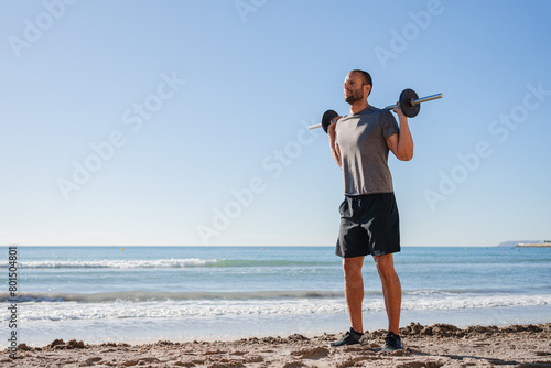 young man does exercises on the beach outdoors