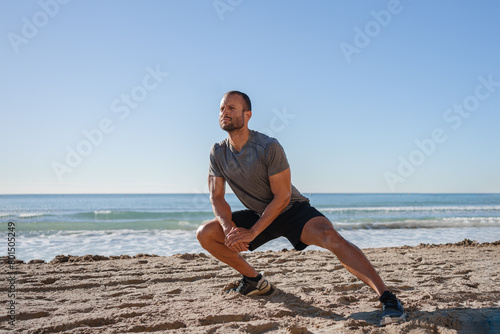 young man does exercises on the beach outdoors (ID: 801505249)