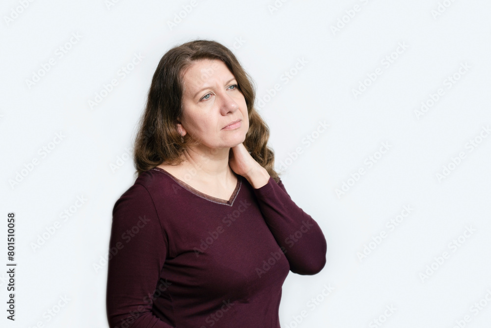 A sad middle-aged woman on a light background holds her neck, massages herself, the woman has a neck pain, a cold, a nerve. The concept of health after 40 years A sad middle-aged woman on a light background holds her neck, massages herself, the woman has a neck pain, a cold, a nerve. The concept of health after 40 years