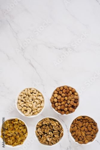 Various nuts and dried fruits in white bowls