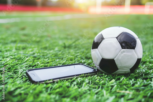 Soccer ball and smart phone on green grass field. concept of a live online broadcast of a football match, 5G technology