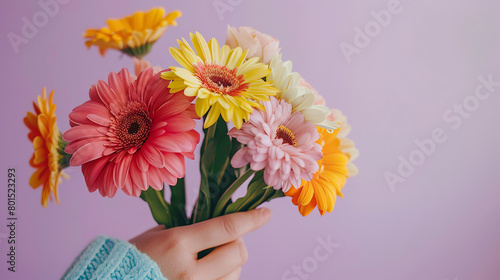 Crop anonymous person demonstrating bunch of colorful flowers against light purple background