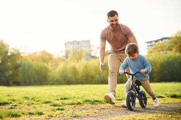 Bicycle, having fun. Happy father with son are on the field at summertime