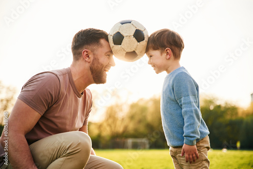 Soccer ball, holding it by heads, fun. Happy father with son are on the field at summertime © standret