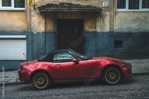 a red sports car is parked on the street
 photo