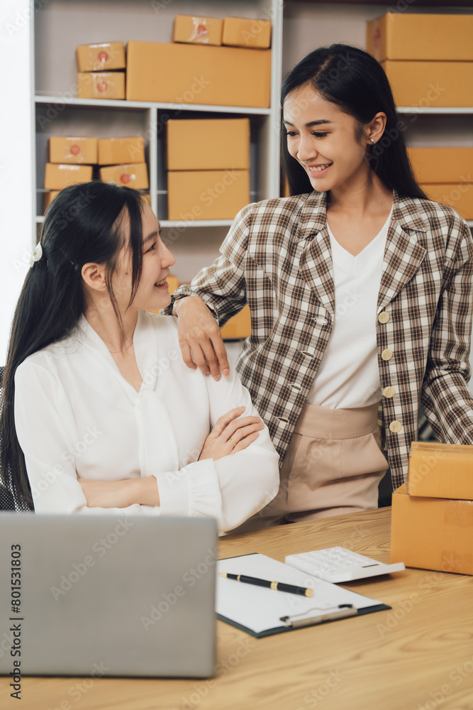 Asian businesswoman using laptop computer checking customer's shipping box online at home. SME startup. Small business entrepreneur, freelancer. Online business, SME work