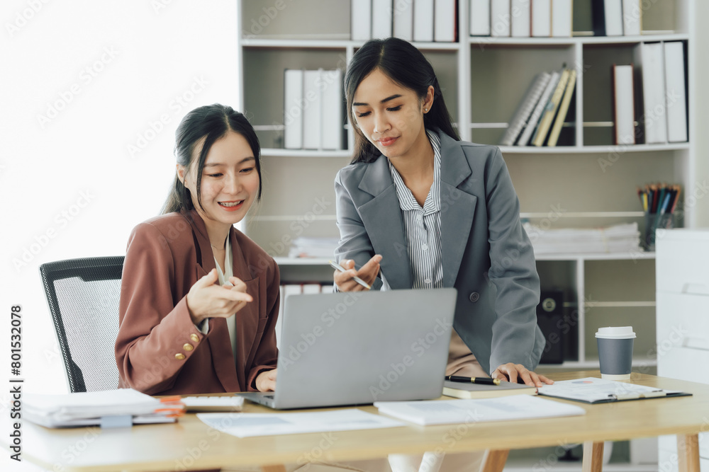 Two young Asian business woman talk, consult, discuss working with new startup project idea presentation analyze plan marketing and investment in the office.