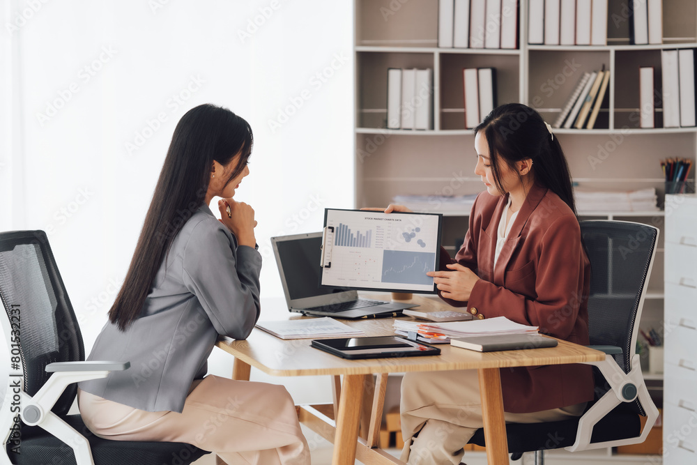 Two young Asian business woman talk, consult, discuss working with new startup project idea presentation analyze plan marketing and investment in the office. Two young Asian business woman talk, consult, discuss working with new startup project idea presentation analyze plan marketing and investment in the office.