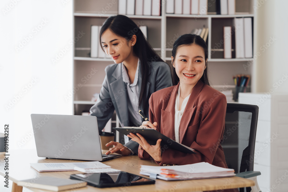Two young Asian business woman talk, consult, discuss working with new startup project idea presentation analyze plan marketing and investment in the office. Two young Asian business woman talk, consult, discuss working with new startup project idea presentation analyze plan marketing and investment in the office.