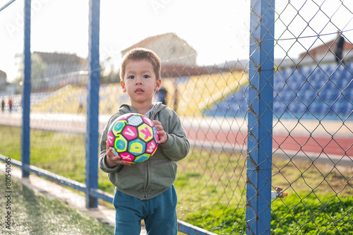 Toddler with a ball by the fence